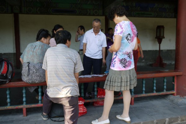 locals relaxing in the park playing a traditional chinese tile game